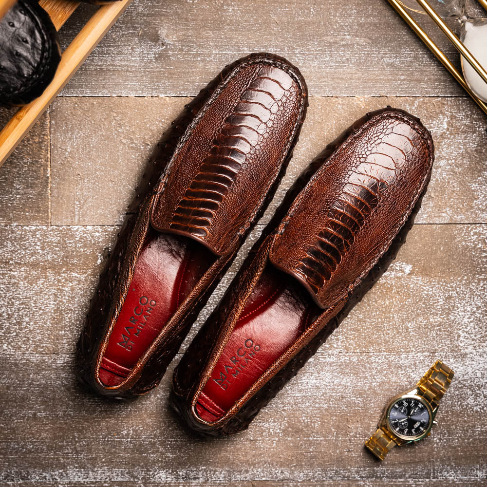 The Alba Kango Tabac by Marco Di Milano: brown textured leather loafers with visible stitching, one flat and one side-propped to reveal the sole—luxury footwear with artisanal hand-painted finishes.