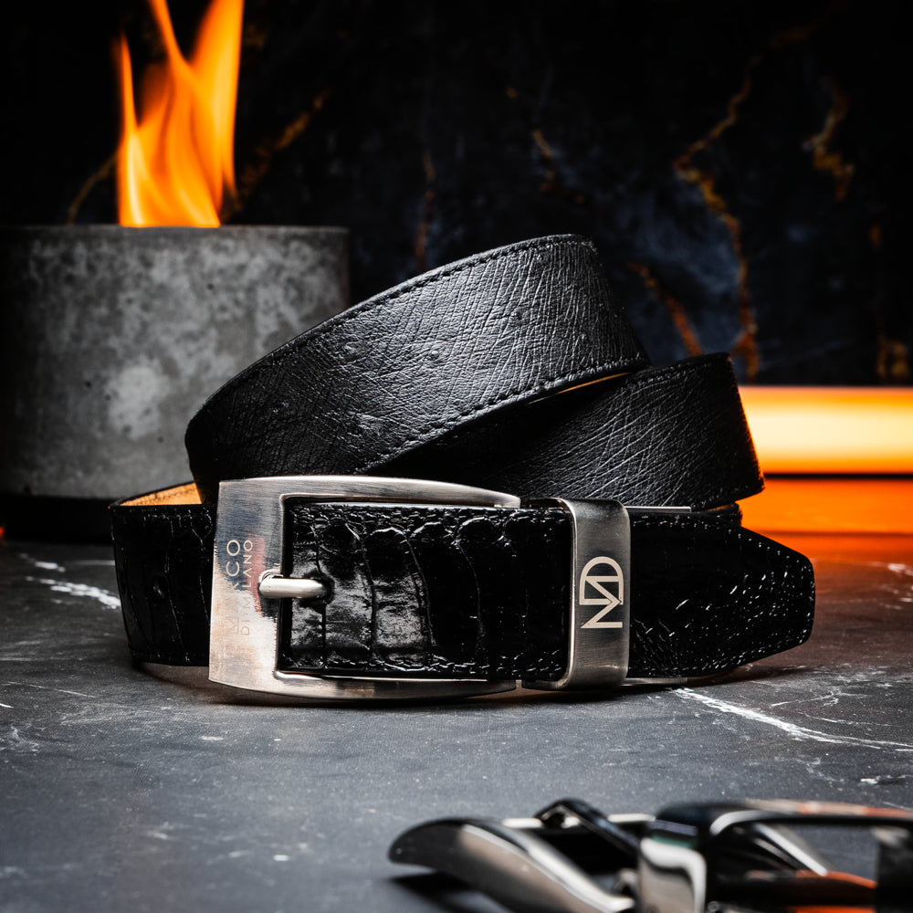 Alessio Belt Black by Marco Di Milano—a handcrafted leather belt in black with a textured finish and a silver buckle engraved with “ATELIER MILANO.” The belt is artfully coiled in a loose loop against a white background.