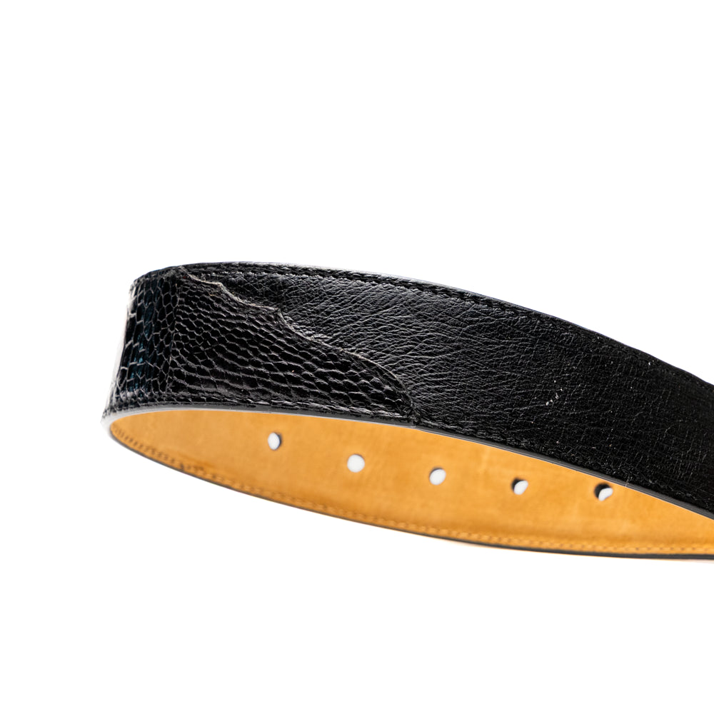 Alessio Belt Black by Marco Di Milano—a handcrafted leather belt in black with a textured finish and a silver buckle engraved with “ATELIER MILANO.” The belt is artfully coiled in a loose loop against a white background.