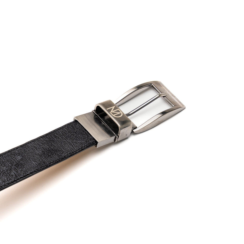 Alessio Belt Black by Marco Di Milano—a handcrafted leather belt in black with a textured finish and a silver buckle engraved with “ATELIER MILANO.” The belt is artfully coiled in a loose loop against a white background.