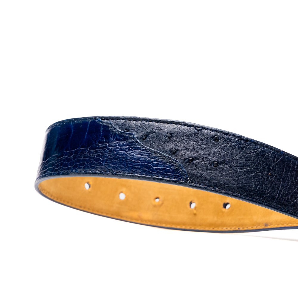 The Alessio Belt Navy by Marco Di Milano is a coiled blue handcrafted luxury belt with a silver buckle, featuring both smooth and textured crocodile-patterned sections.