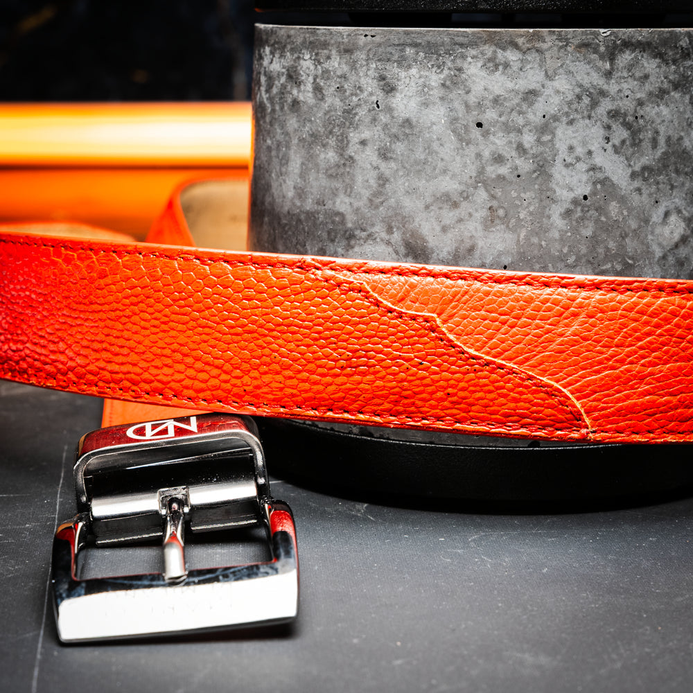 Close-up of the Alessio Belt Orange by Marco Di Milano, a handcrafted luxury accessory made from genuine orange ostrich leather, highlighting its distinctive texture and five adjustment holes against a white background.