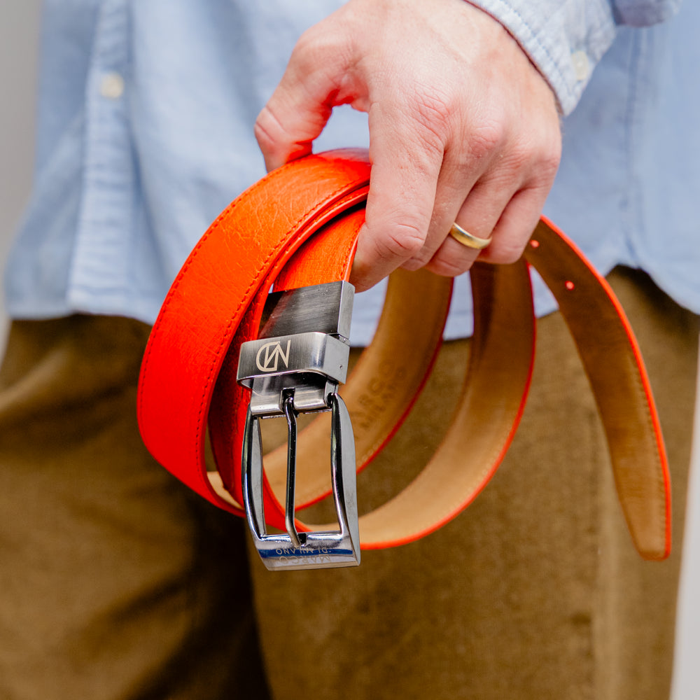 Close-up of the Alessio Belt Orange by Marco Di Milano, a handcrafted luxury accessory made from genuine orange ostrich leather, highlighting its distinctive texture and five adjustment holes against a white background.