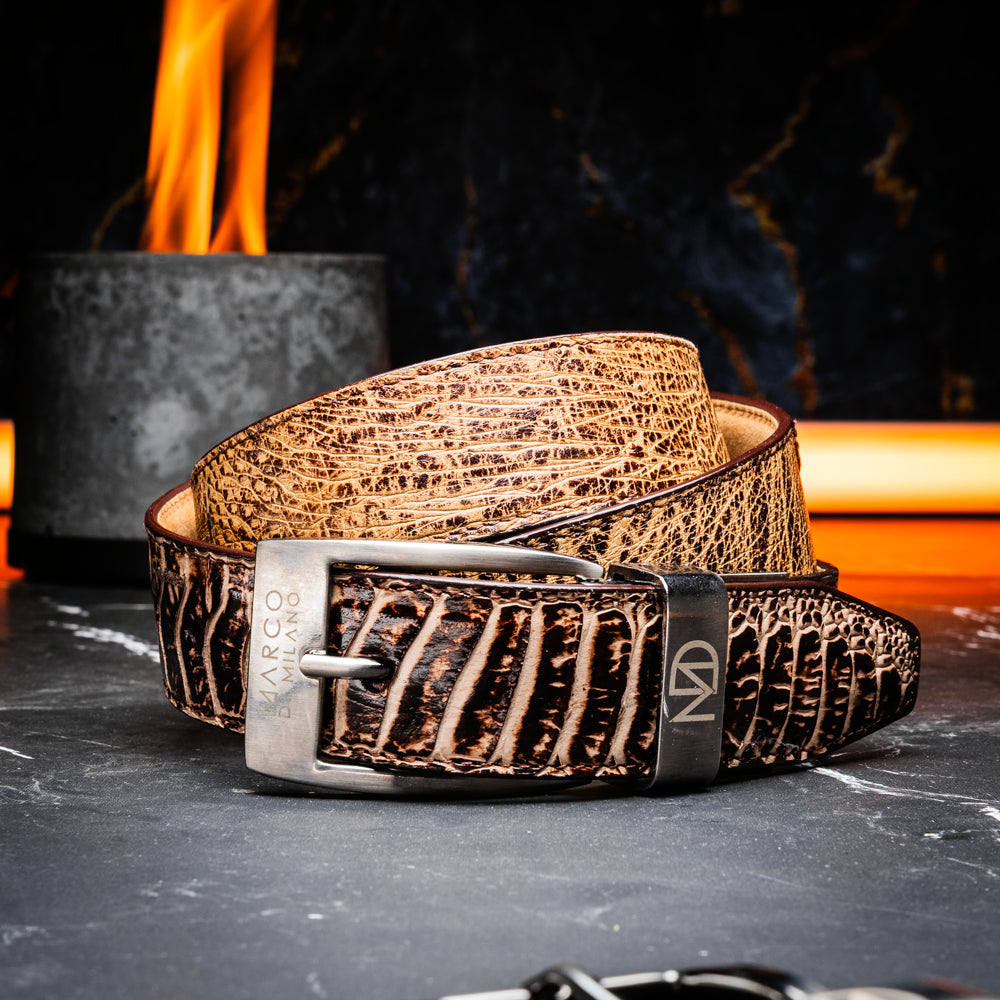 The Alessio Belt Orix by Marco Di Milano, featuring textured genuine ostrich leather in brown and a silver buckle, is coiled to display both its inside and outside surfaces.