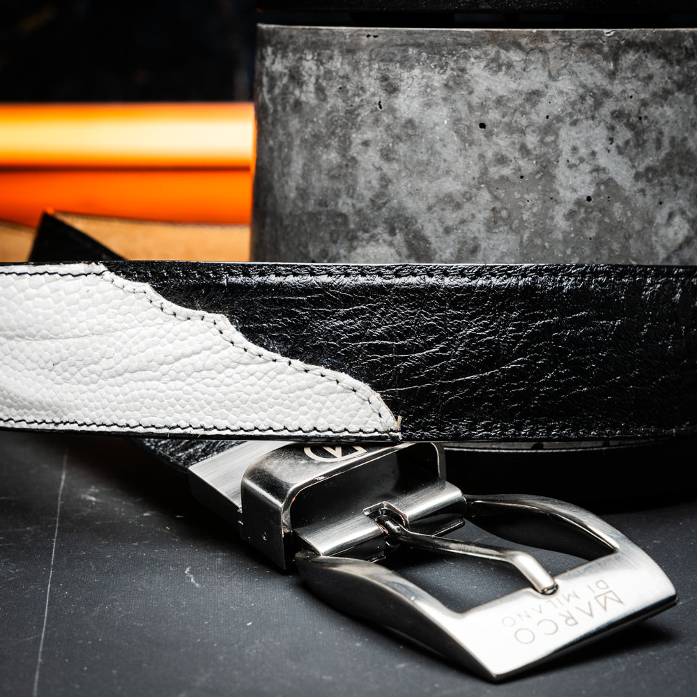 The Alessio Belt White / Black by Marco Di Milano showcases both a black and a white genuine ostrich belt, coiled together with visible textures and silver buckles engraved with the brand’s logo.