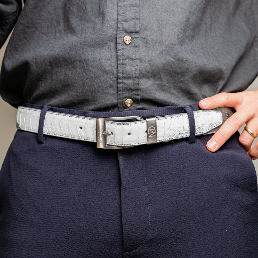 Introducing the Alessio Belt White / Gray by Marco Di Milano—a handcrafted luxury accessory featuring a textured gray exotic leather strap and a distinctive white, ridged front. The metallic buckle is engraved with the Marco Di Milano logo, accentuating the exquisite craftsmanship of this elegant belt.