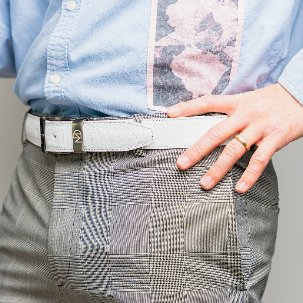 Introducing the Alessio Belt White by Marco Di Milano—a handcrafted luxury belt in pristine white leather, adorned with a silver buckle engraved with the brand’s iconic signature, elegantly coiled on a white background.