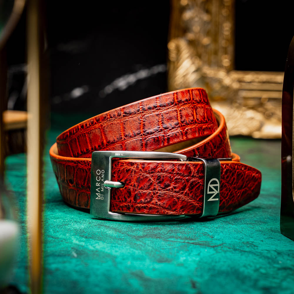 A rolled-up, textured rustic cognac leather Emilio Belt by Marco Di Milano with a silver rectangular buckle engraved with the brand name.