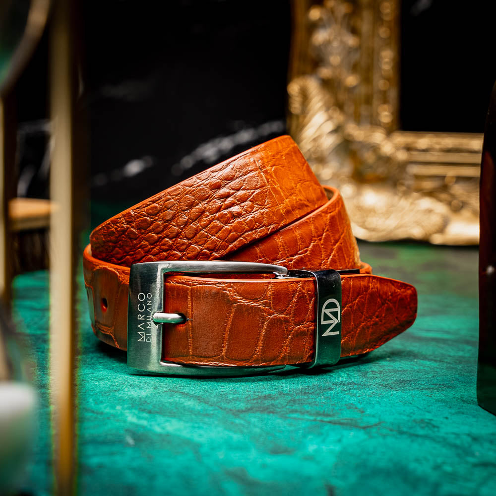 The Emilio Belt Cognac by Marco Di Milano features textured cognac leather and a silver buckle engraved with the brand name, shown on a white background—a refined accessory that complements Marco Di Milano’s luxury footwear.