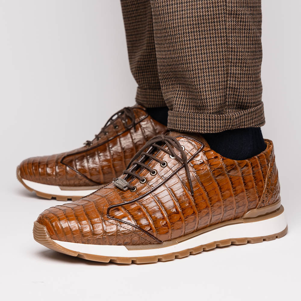 The Marco Di Milano Alonzo Bay Apache sneakers feature brown genuine caiman crocodile leather, white midsoles, brown rubber outsoles, a lace-up design, and a textured pattern—luxury footwear ideal for any occasion.