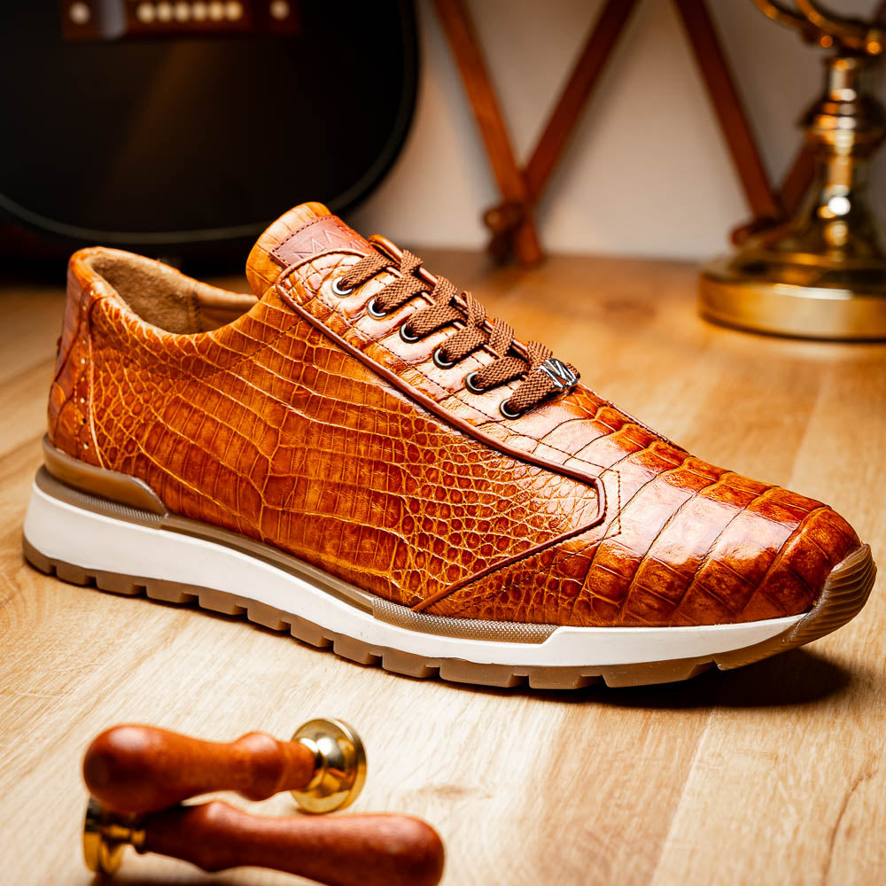 The Alonzo Cognac sneaker by Marco Di Milano features a hand-painted brown caiman crocodile-patterned leather upper and a white-brown rubber sole—luxury footwear for discerning tastes, shown in a sleek side view.