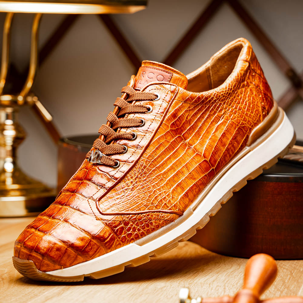 The Alonzo Cognac sneaker by Marco Di Milano features a hand-painted brown caiman crocodile-patterned leather upper and a white-brown rubber sole—luxury footwear for discerning tastes, shown in a sleek side view.