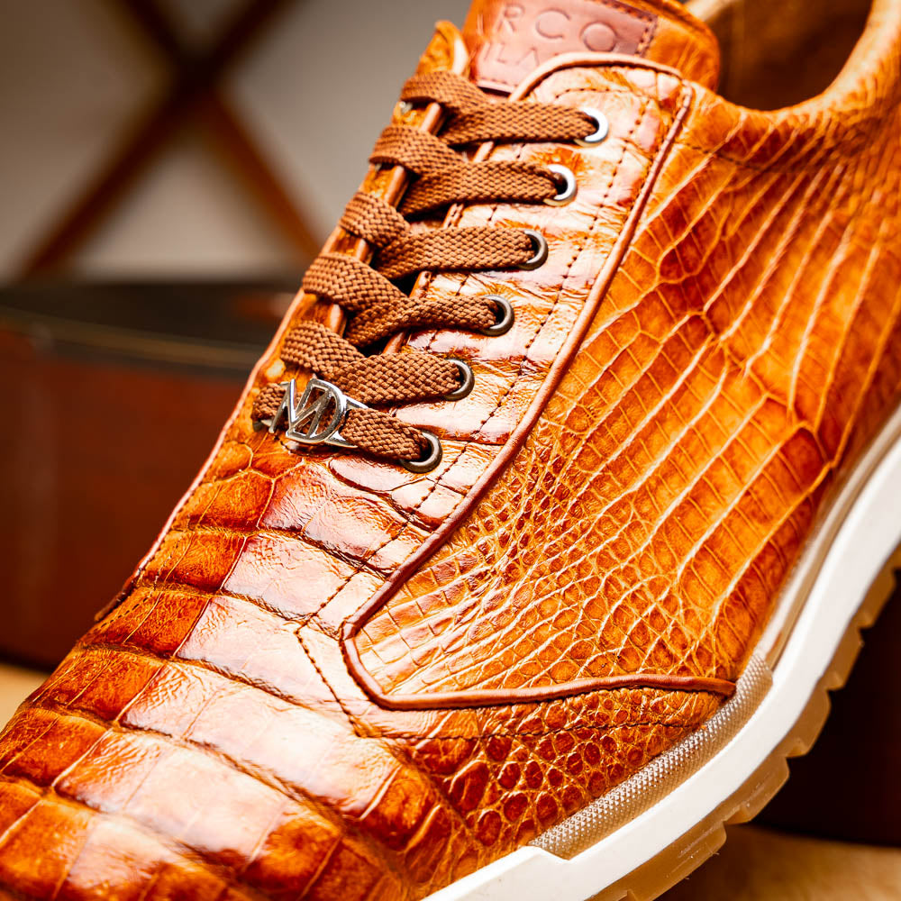 The Alonzo Cognac sneaker by Marco Di Milano features a hand-painted brown caiman crocodile-patterned leather upper and a white-brown rubber sole—luxury footwear for discerning tastes, shown in a sleek side view.