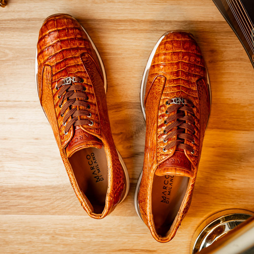 The Alonzo Cognac sneaker by Marco Di Milano features a hand-painted brown caiman crocodile-patterned leather upper and a white-brown rubber sole—luxury footwear for discerning tastes, shown in a sleek side view.