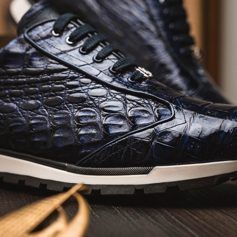 The Alonzo Navy by Marco Di Milano is a luxury men's sneaker in genuine caiman crocodile leather, featuring black laces, a hand-painted finish, white midsole, and black textured outsole.