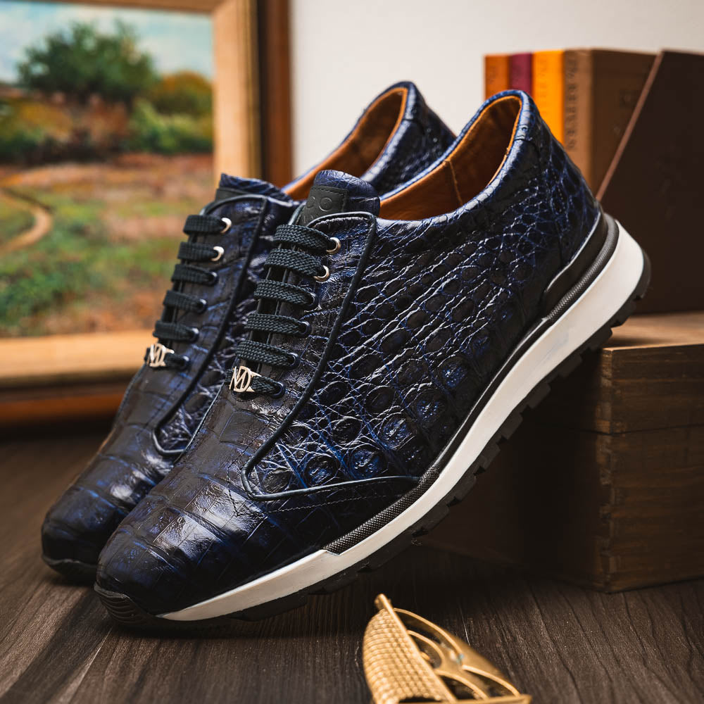 The Alonzo Navy by Marco Di Milano is a luxury men's sneaker in genuine caiman crocodile leather, featuring black laces, a hand-painted finish, white midsole, and black textured outsole.
