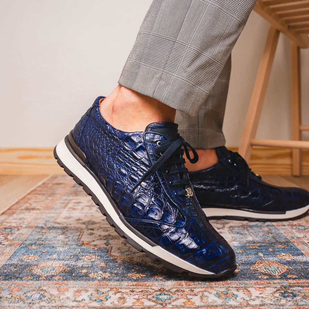 The Alonzo Navy by Marco Di Milano is a luxury men's sneaker in genuine caiman crocodile leather, featuring black laces, a hand-painted finish, white midsole, and black textured outsole.