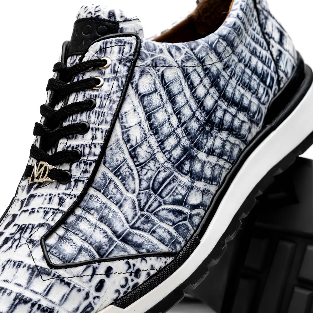 The Alonzo Newspaper sneakers by Marco Di Milano feature genuine caiman crocodile in white and black with a hand-painted finish, black laces, and black rubber soles, displayed with one shoe propped on the other against a white background.