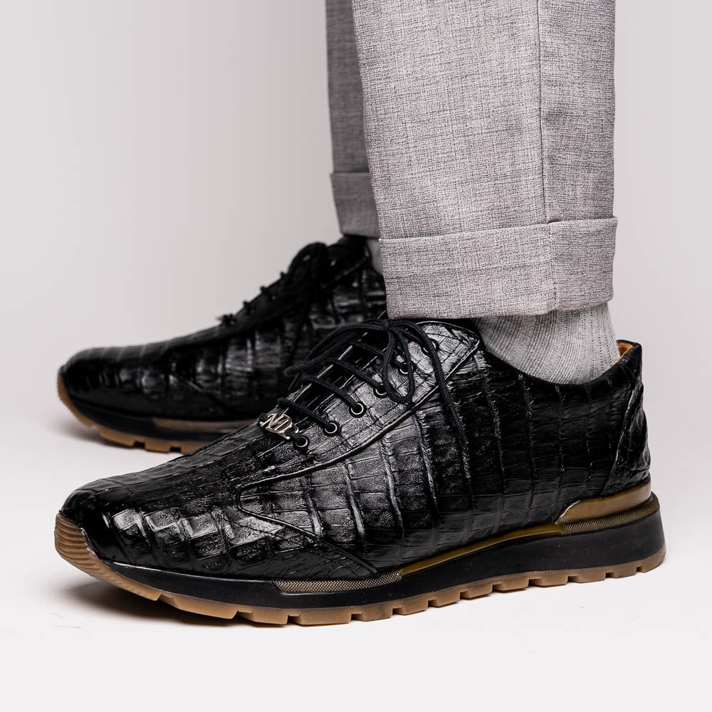 The Alonzo Black by Marco Di Milano: luxury men's sneakers crafted from black genuine caiman crocodile leather with a hand-painted finish and brown rubber soles—one shoe upright, the other leaning against it.