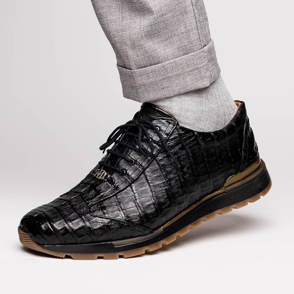 The Alonzo Black by Marco Di Milano: luxury men's sneakers crafted from black genuine caiman crocodile leather with a hand-painted finish and brown rubber soles—one shoe upright, the other leaning against it.