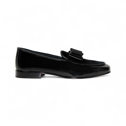 The Duca Di Matiste Duca Amalfi Black loafer features black patent leather, a low heel, and a decorative bow, showcased here against a white background.
