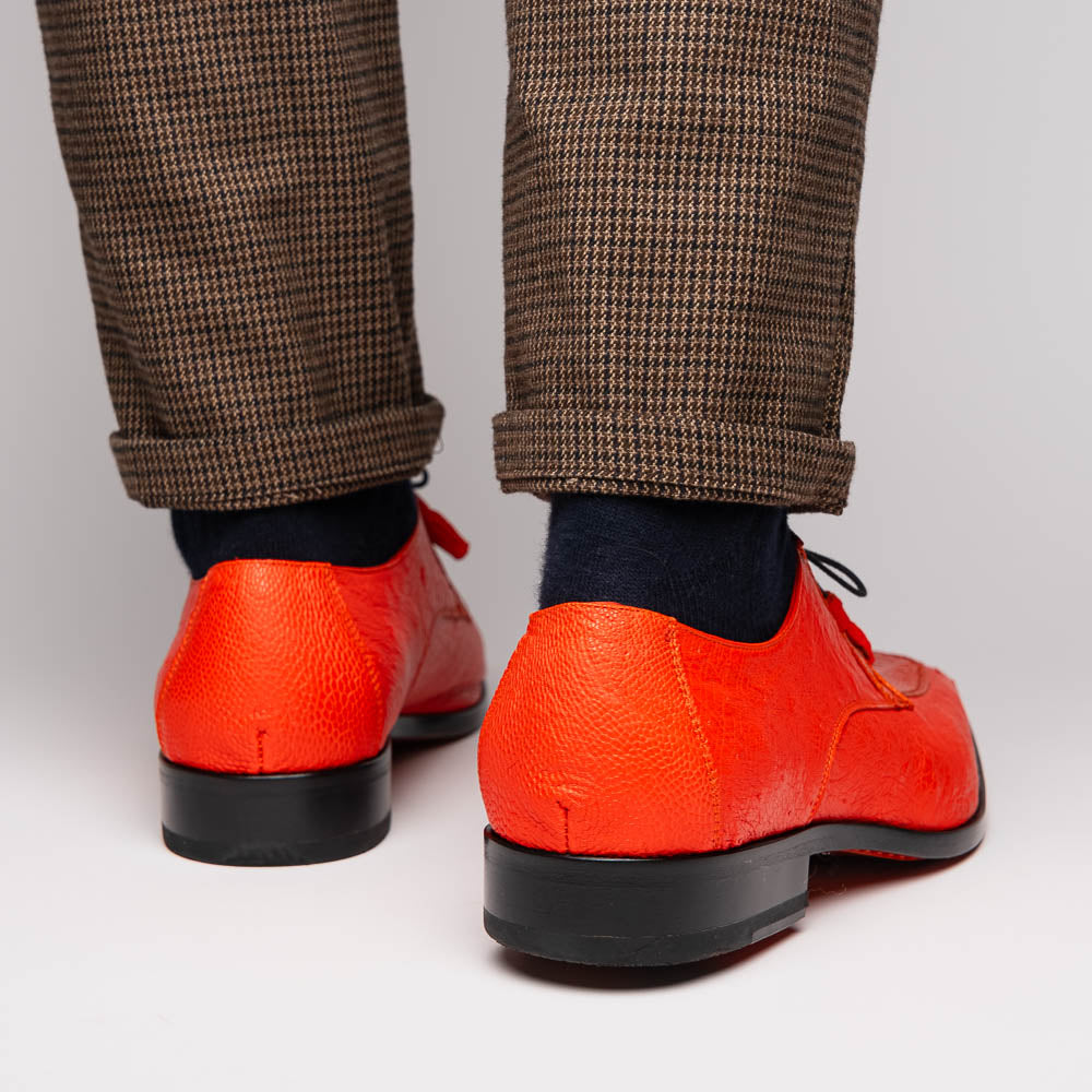 The Andretti Orange by Marco Di Milano are vibrant orange leather dress shoes with black laces and textured detailing, one upright and one showing the branded sole—ideal luxury footwear for men.