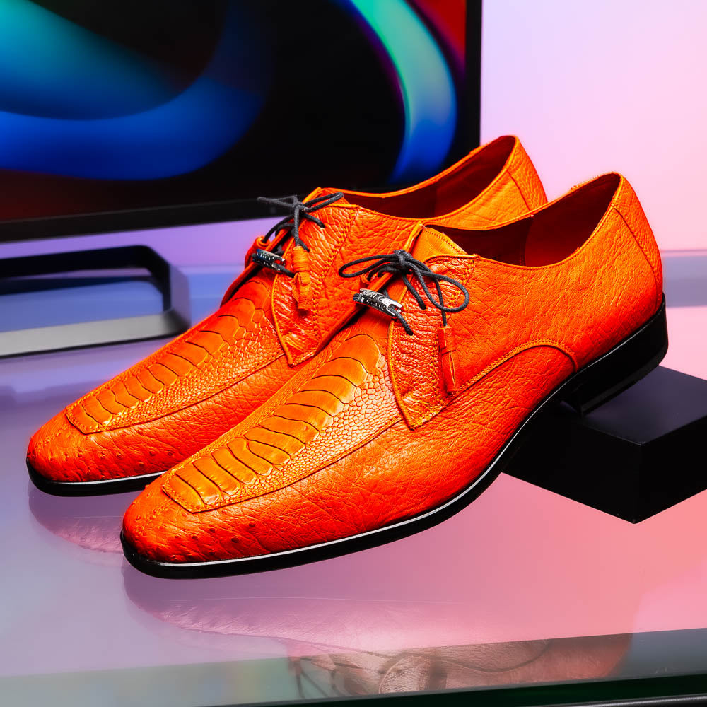 The Andretti Orange by Marco Di Milano are vibrant orange leather dress shoes with black laces and textured detailing, one upright and one showing the branded sole—ideal luxury footwear for men.