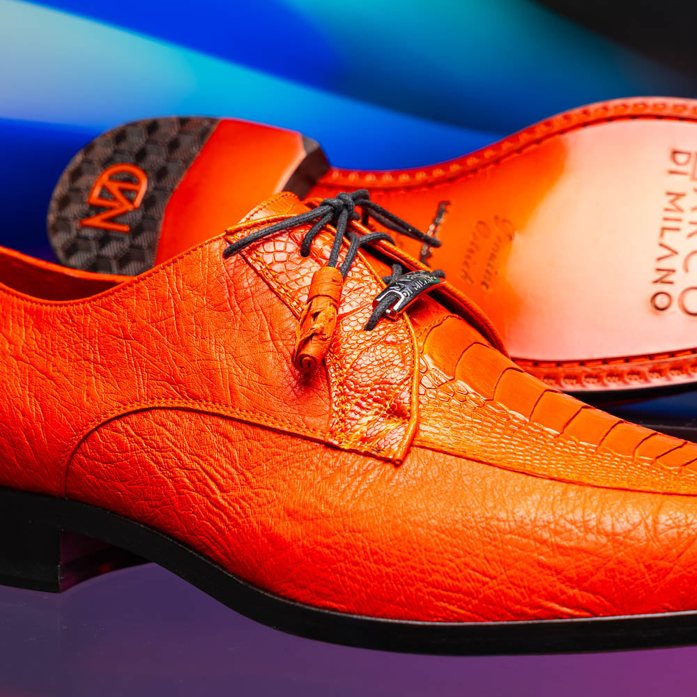 The Andretti Orange by Marco Di Milano are vibrant orange leather dress shoes with black laces and textured detailing, one upright and one showing the branded sole—ideal luxury footwear for men.