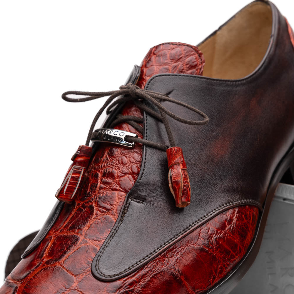 The Anzio Rustic Cognac by Marco Di Milano is a men's dress shoe featuring red and brown crocodile-patterned leather, lace-up closure, tassel accents, and leather soles—an elevated choice in luxury footwear.