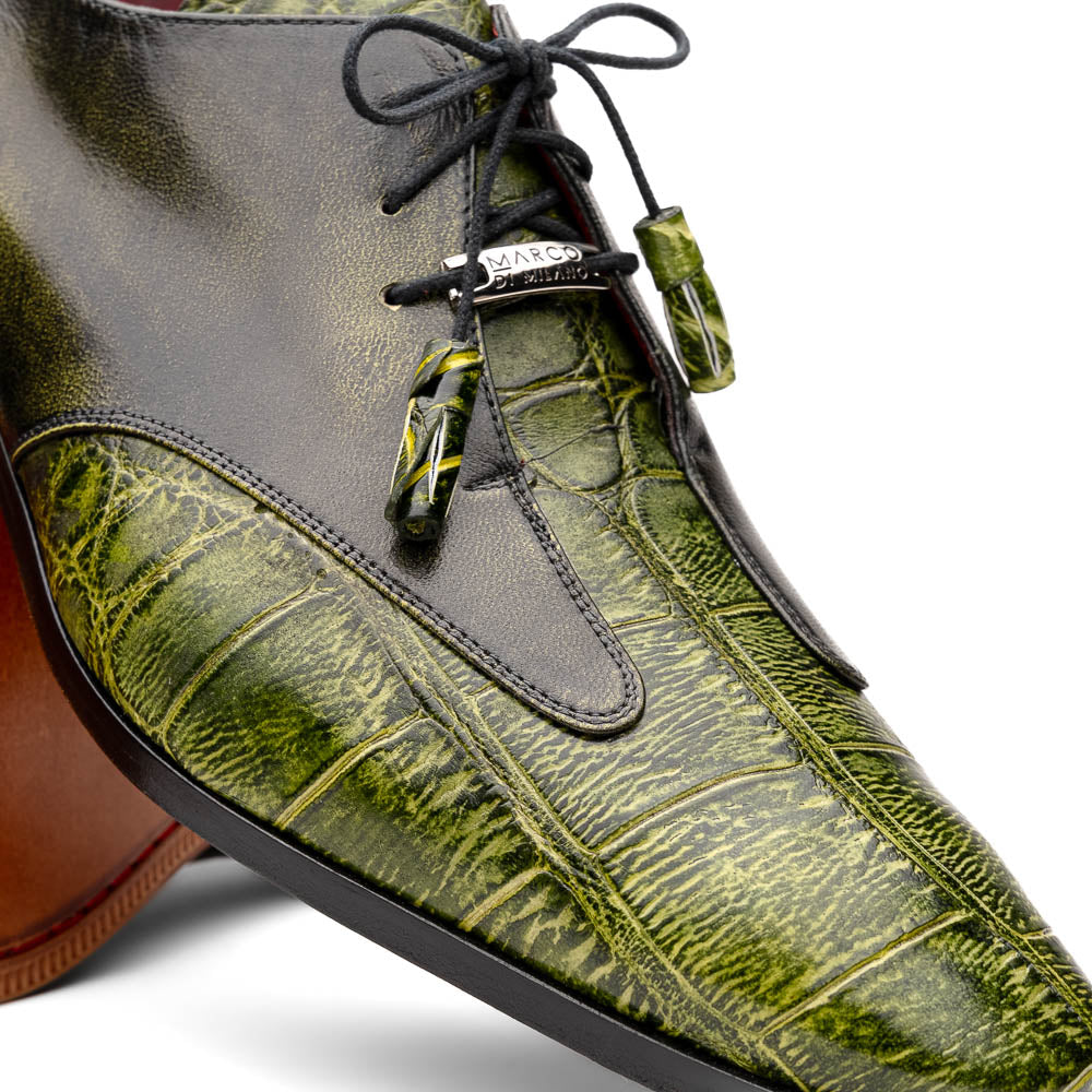 A pair of Anzio Rustic Green men's dress shoes by Marco Di Milano, featuring a green textured finish, black laces, and brown leather soles—one upright and one lying on its side.