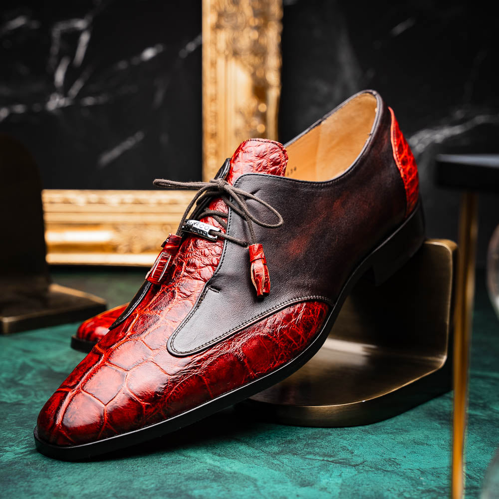 The Anzio Rustic Cognac by Marco Di Milano is a men's dress shoe featuring red and brown crocodile-patterned leather, lace-up closure, tassel accents, and leather soles—an elevated choice in luxury footwear.