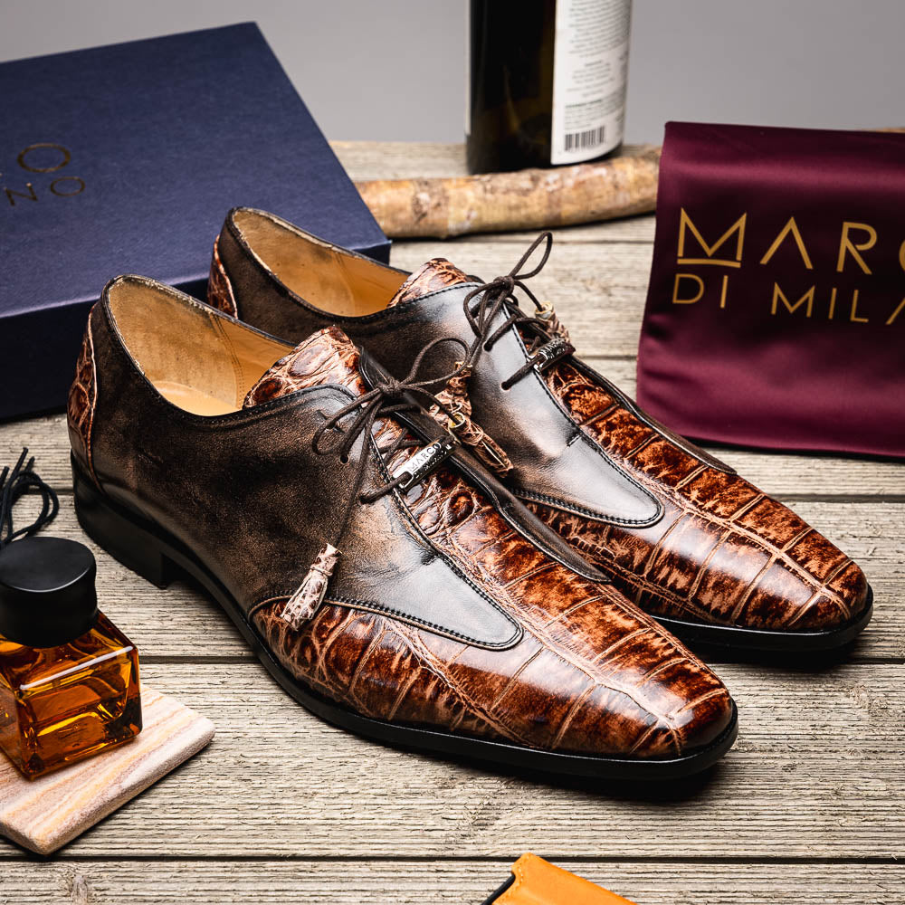 A pair of Anzio Rustic Orix brown leather dress shoes by Marco Di Milano, featuring a textured crocodile pattern—one upright, the other showing a smooth tan sole—represent true luxury men's footwear.