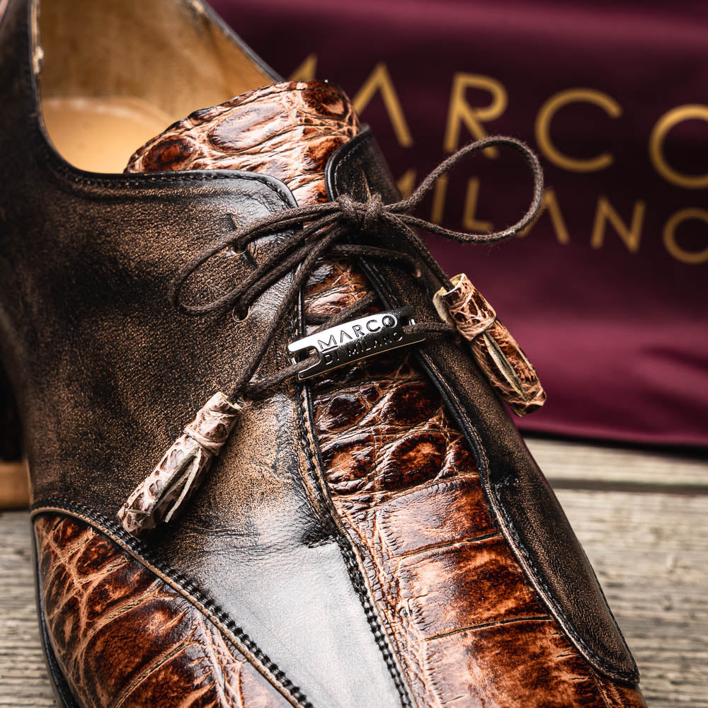 A pair of Anzio Rustic Orix brown leather dress shoes by Marco Di Milano, featuring a textured crocodile pattern—one upright, the other showing a smooth tan sole—represent true luxury men's footwear.