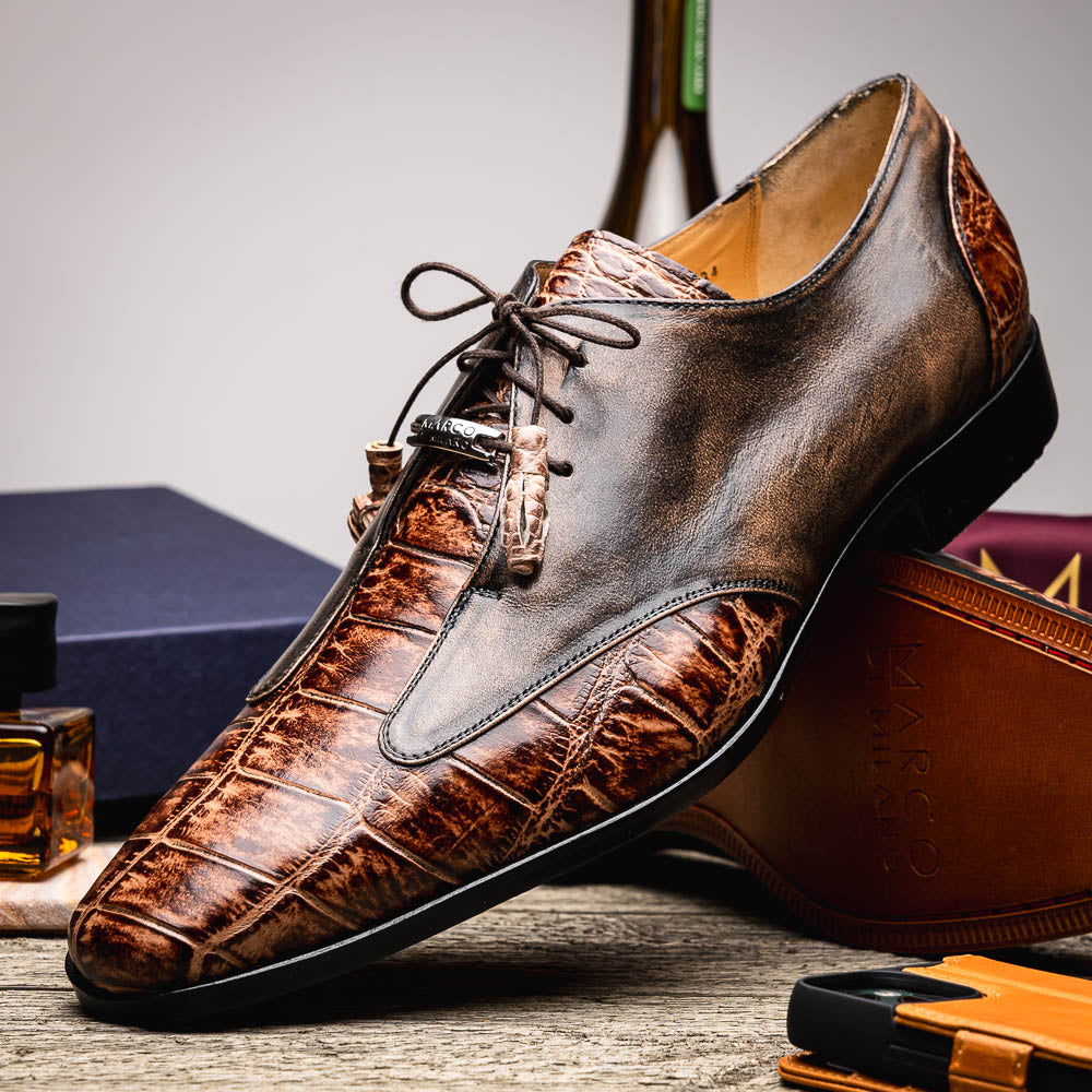 A pair of Anzio Rustic Orix brown leather dress shoes by Marco Di Milano, featuring a textured crocodile pattern—one upright, the other showing a smooth tan sole—represent true luxury men's footwear.