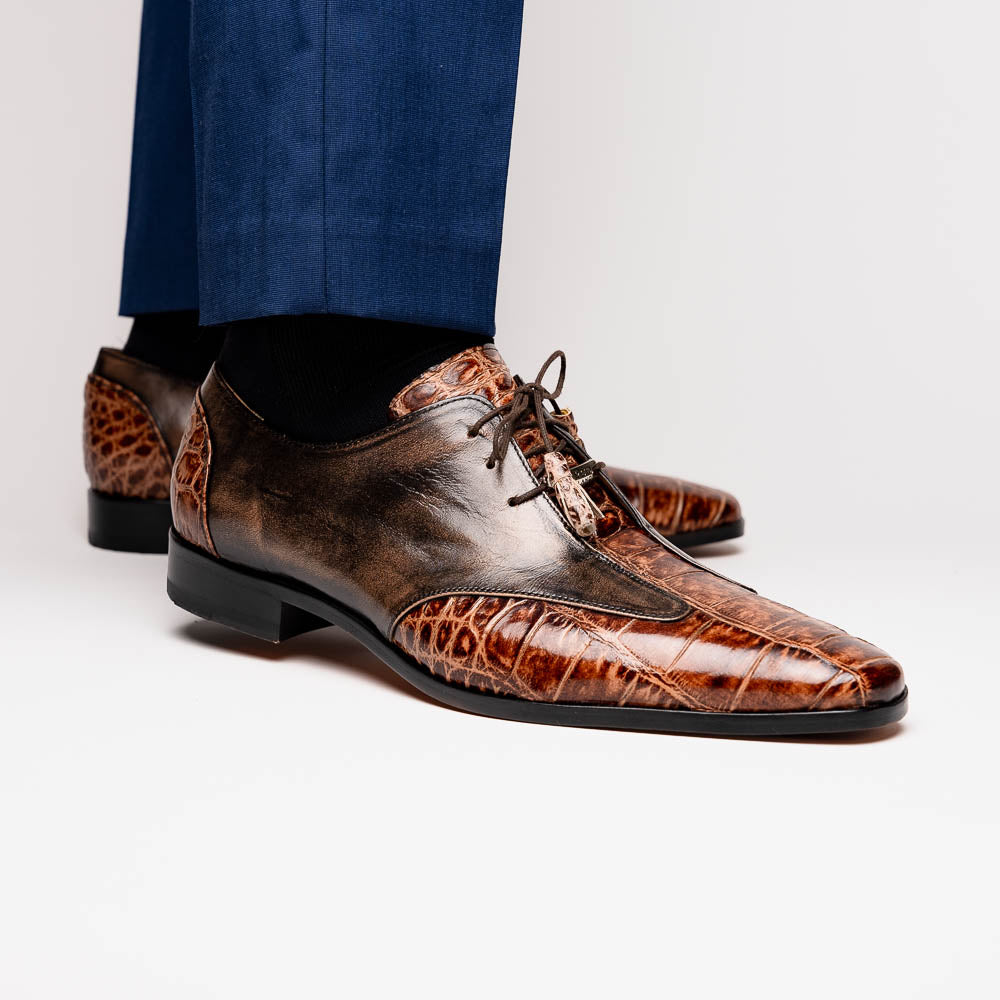 A pair of Anzio Rustic Orix brown leather dress shoes by Marco Di Milano, featuring a textured crocodile pattern—one upright, the other showing a smooth tan sole—represent true luxury men's footwear.