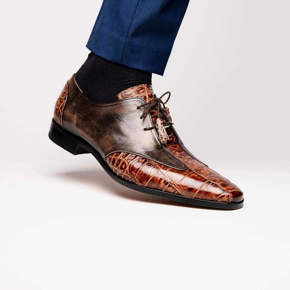 A pair of Anzio Rustic Orix brown leather dress shoes by Marco Di Milano, featuring a textured crocodile pattern—one upright, the other showing a smooth tan sole—represent true luxury men's footwear.
