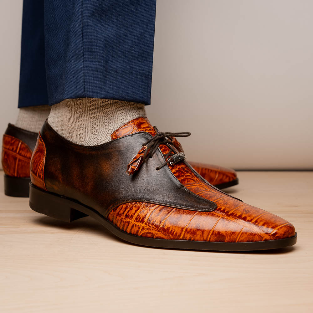 Step out in style with the Marco Di Milano Anzio Rustic Brandy men's leather dress shoes, showcasing a brown and orange crocodile pattern, lace-up closure, and "MARCO" branding—perfect for those who appreciate luxury footwear.