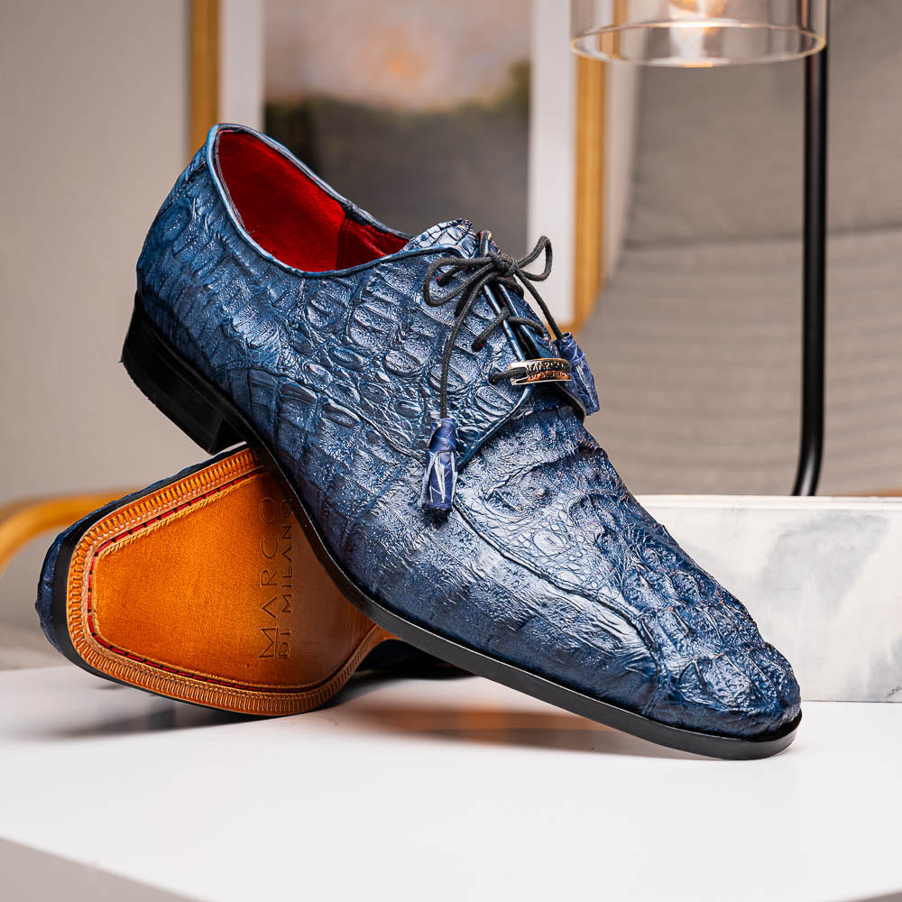 The Apricena Navy by Marco Di Milano are blue textured luxury men's dress shoes with black laces, red interior lining, and branded tan leather soles—crafted to evoke the refined look of genuine caiman crocodile shoes.