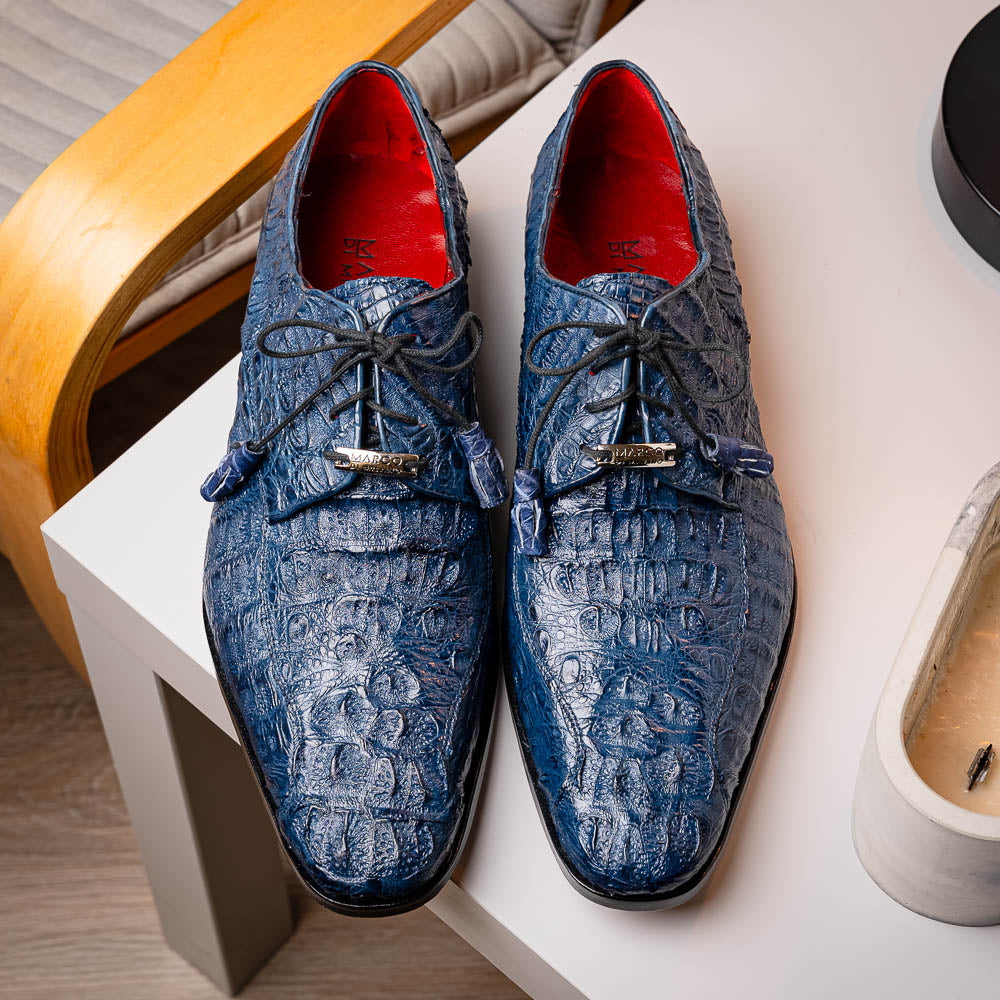 The Apricena Navy by Marco Di Milano are blue textured luxury men's dress shoes with black laces, red interior lining, and branded tan leather soles—crafted to evoke the refined look of genuine caiman crocodile shoes.