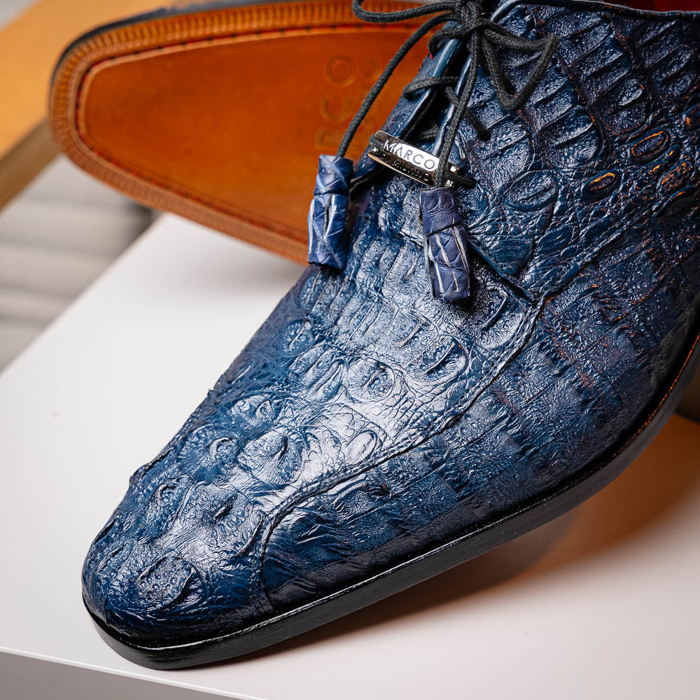 The Apricena Navy by Marco Di Milano are blue textured luxury men's dress shoes with black laces, red interior lining, and branded tan leather soles—crafted to evoke the refined look of genuine caiman crocodile shoes.