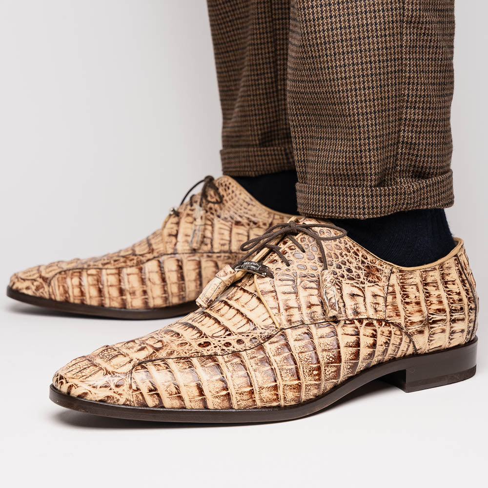 A pair of Marco Di Milano Apricena Rustic Orix luxury dress shoes in beige crocodile pattern, one upright and one on its side revealing the brown sole with embossed branding. Made from genuine caiman crocodile leather for an elegant finish.