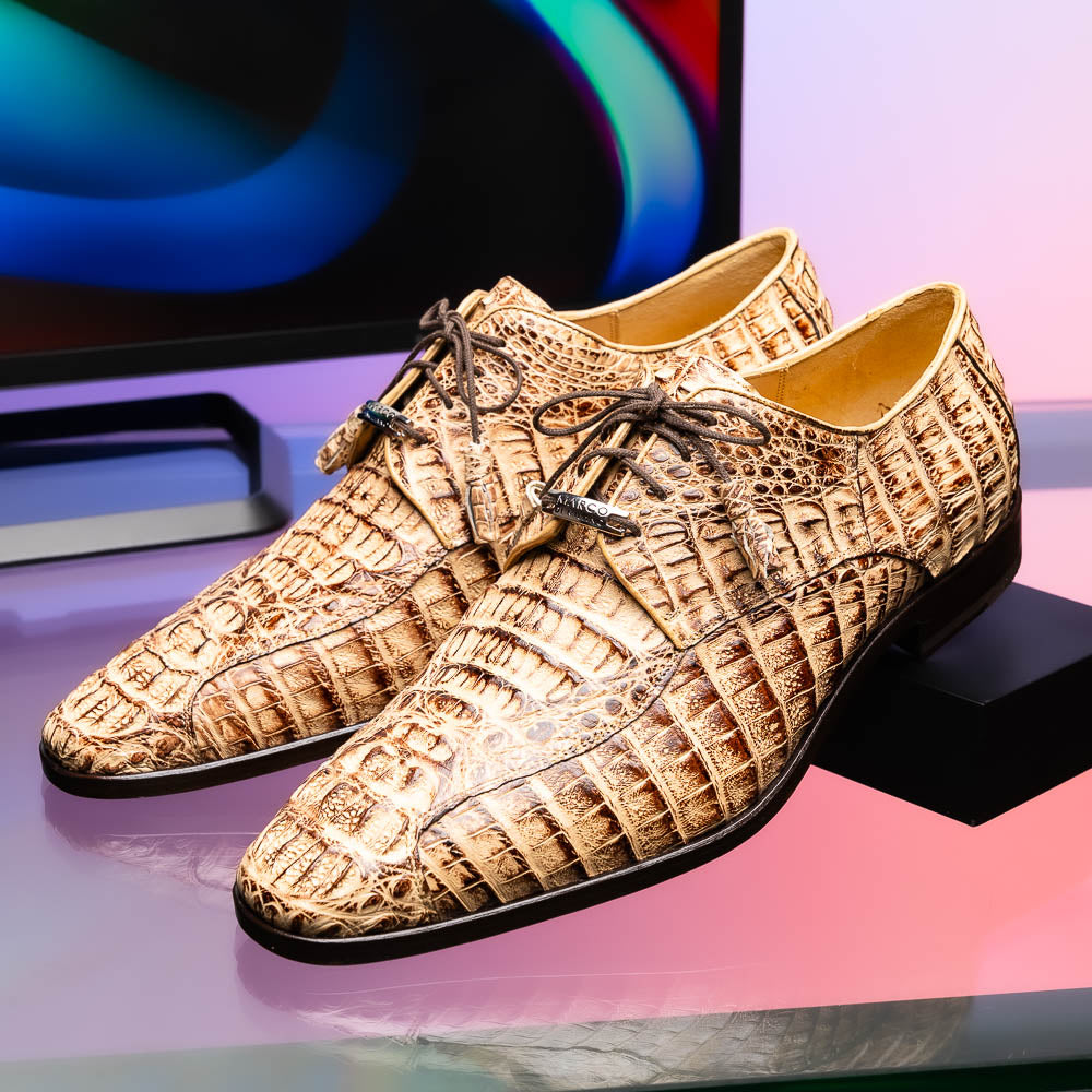 A pair of Marco Di Milano Apricena Rustic Orix luxury dress shoes in beige crocodile pattern, one upright and one on its side revealing the brown sole with embossed branding. Made from genuine caiman crocodile leather for an elegant finish.