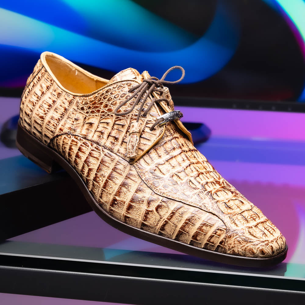 A pair of Marco Di Milano Apricena Rustic Orix luxury dress shoes in beige crocodile pattern, one upright and one on its side revealing the brown sole with embossed branding. Made from genuine caiman crocodile leather for an elegant finish.