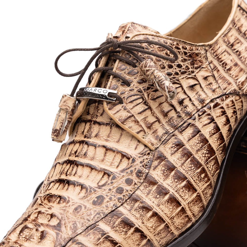 A pair of Marco Di Milano Apricena Rustic Orix luxury dress shoes in beige crocodile pattern, one upright and one on its side revealing the brown sole with embossed branding. Made from genuine caiman crocodile leather for an elegant finish.