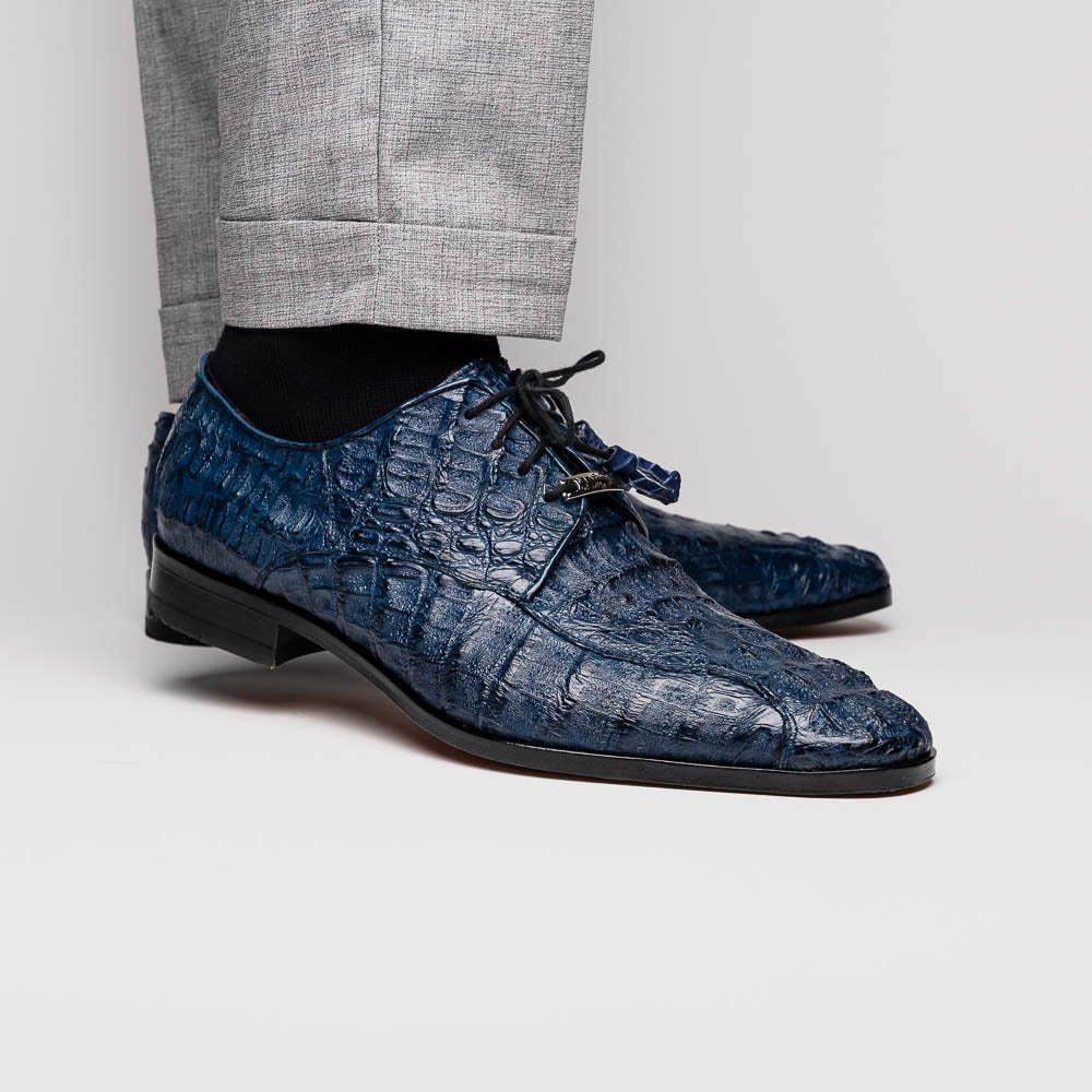 The Apricena Navy by Marco Di Milano are blue textured luxury men's dress shoes with black laces, red interior lining, and branded tan leather soles—crafted to evoke the refined look of genuine caiman crocodile shoes.