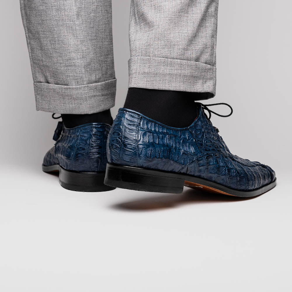 The Apricena Navy by Marco Di Milano are blue textured luxury men's dress shoes with black laces, red interior lining, and branded tan leather soles—crafted to evoke the refined look of genuine caiman crocodile shoes.