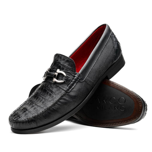 The Adro Black by Marco Di Milano are black textured leather loafers made from genuine exotics, with metal bit detailing and a red inner lining. One shoe stands upright while the other lies on its side to show the sole.