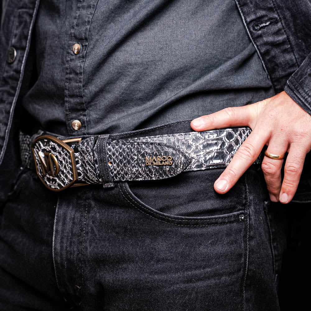 The Arkansas Belt Antique Newspaper by Marco Di Milano features genuine python skin in black and silver, a large gold “MD” buckle, and “MARCO MILANO” text on the tip, fusing exotic style with luxury craftsmanship.