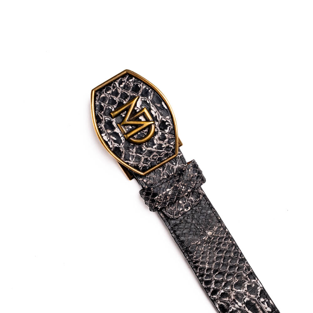 The Arkansas Belt Antique Newspaper by Marco Di Milano features genuine python skin in black and silver, a large gold “MD” buckle, and “MARCO MILANO” text on the tip, fusing exotic style with luxury craftsmanship.