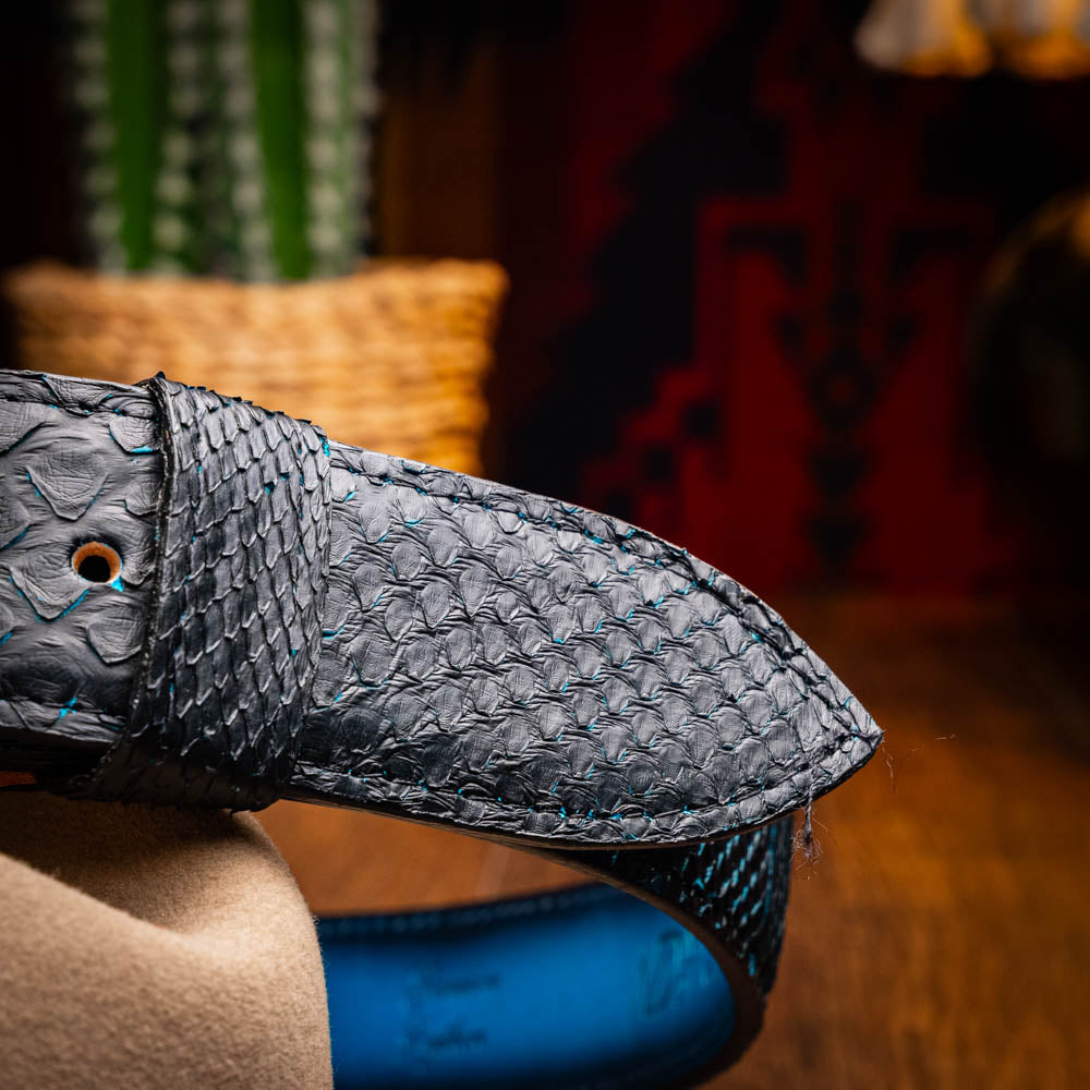The Arkansas Belt Black / Blue by Marco Di Milano features a handcrafted black snakeskin pattern and a gold and black "MD" buckle, displayed against a white background.